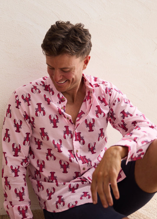 Person wearing a pink shirt with red lobster pattern against a natural background