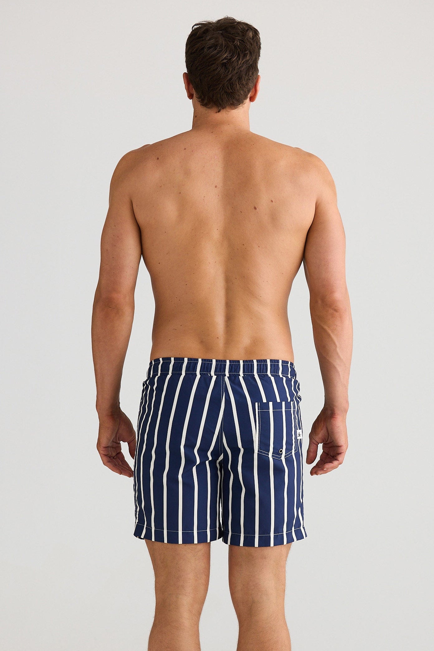 Man wearing navy striped swim shorts on a white background