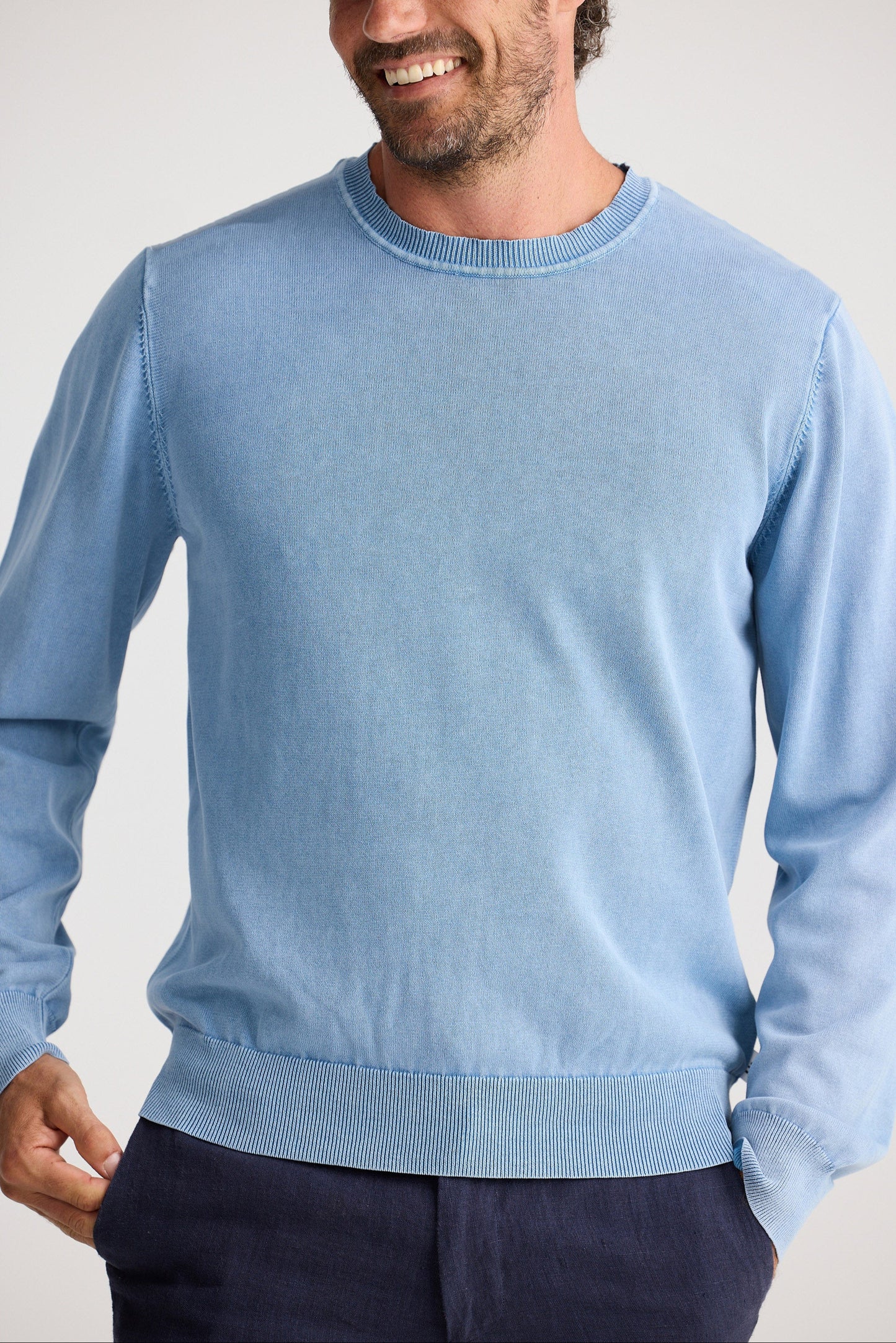 Man wearing a light blue sweater against a plain background