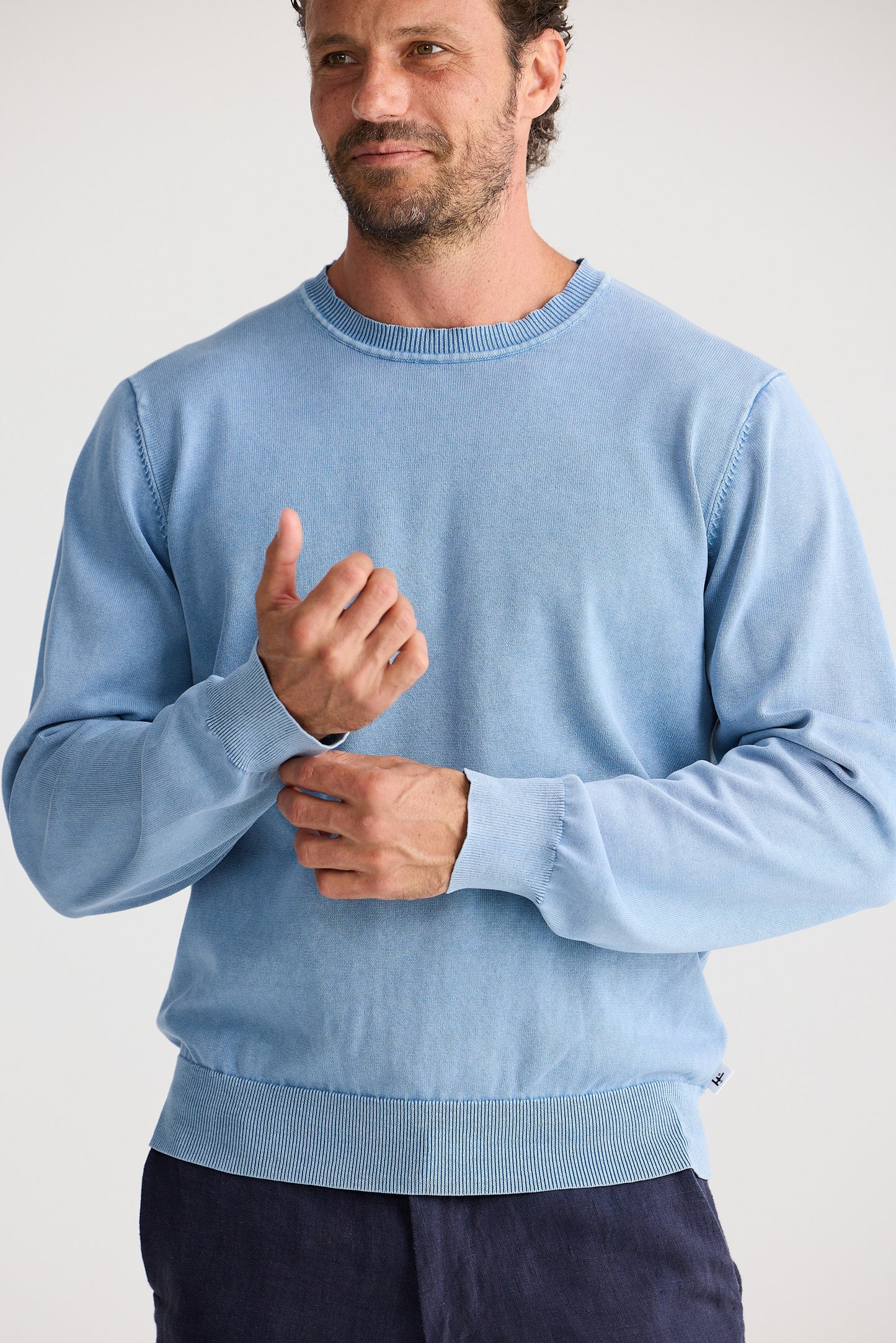 Man wearing a light blue sweater against a plain background