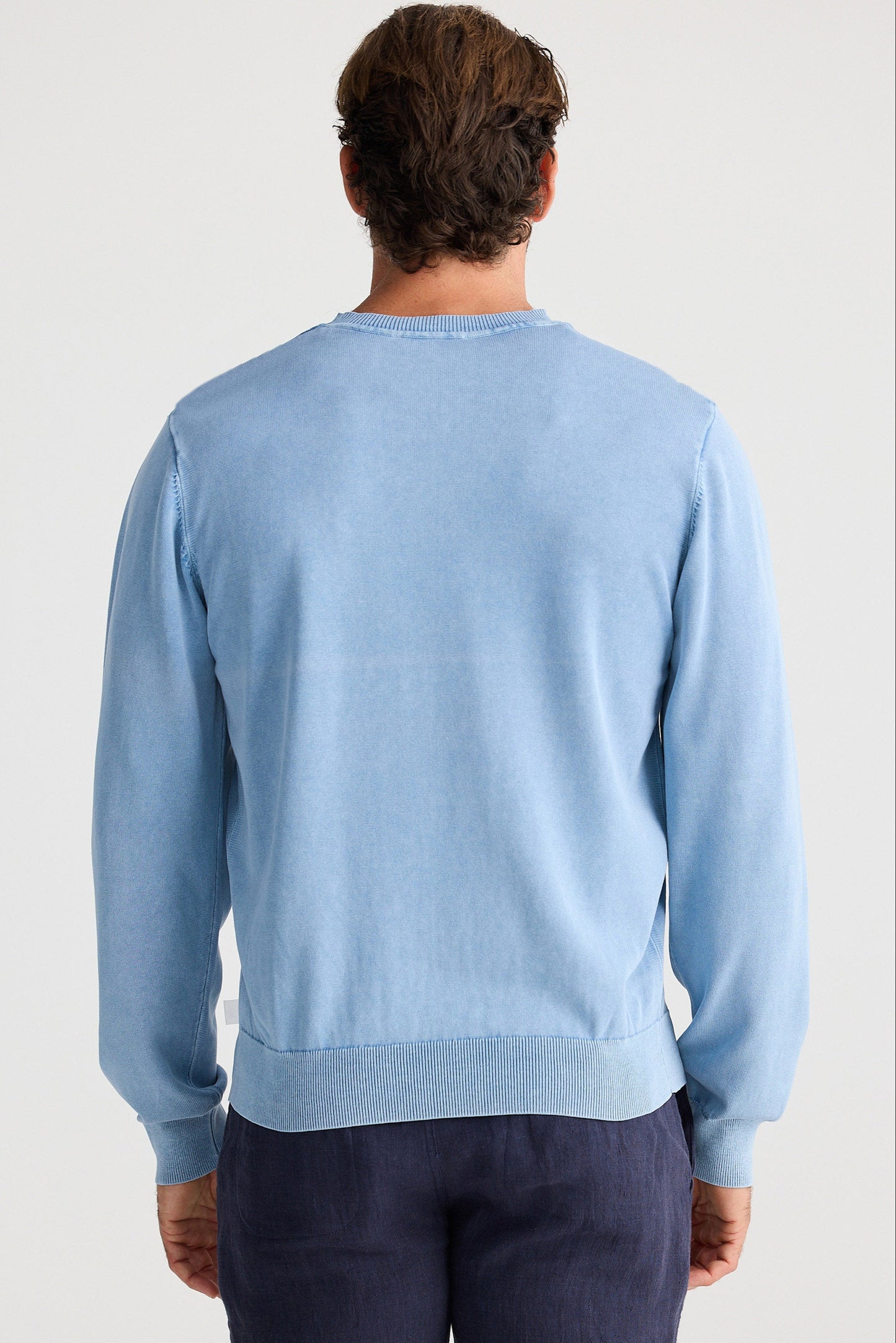 Man wearing a light blue sweater on a plain background