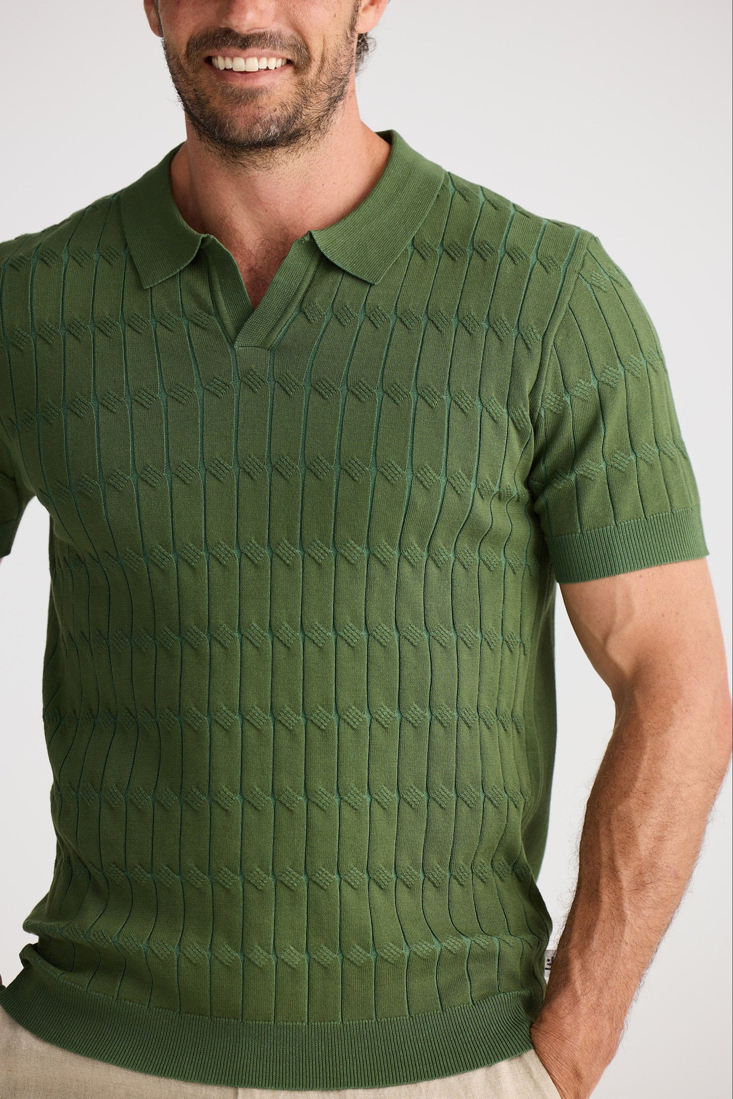 Man wearing a green patterned polo shirt against a plain background