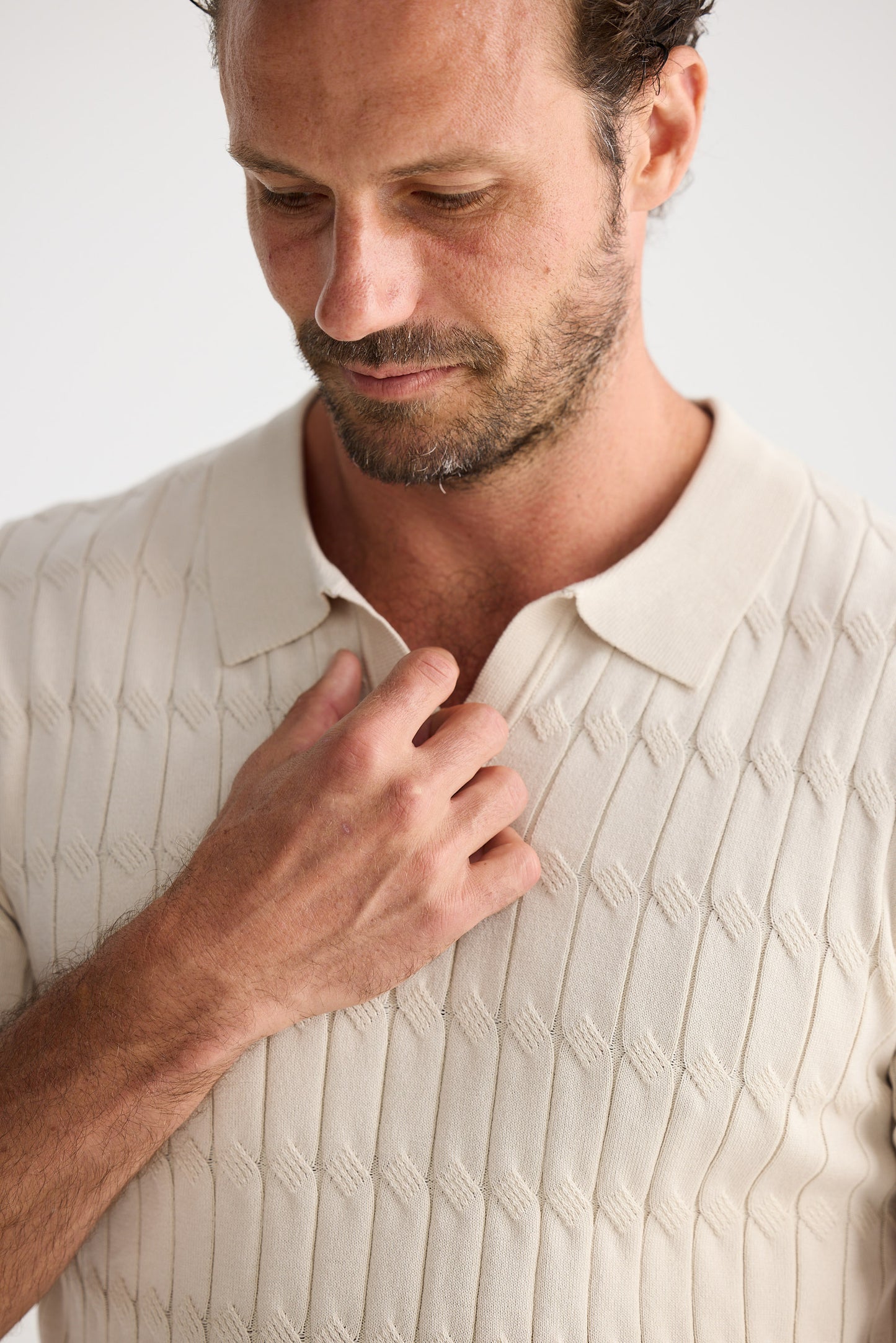 Man wearing a beige textured shirt against a white background