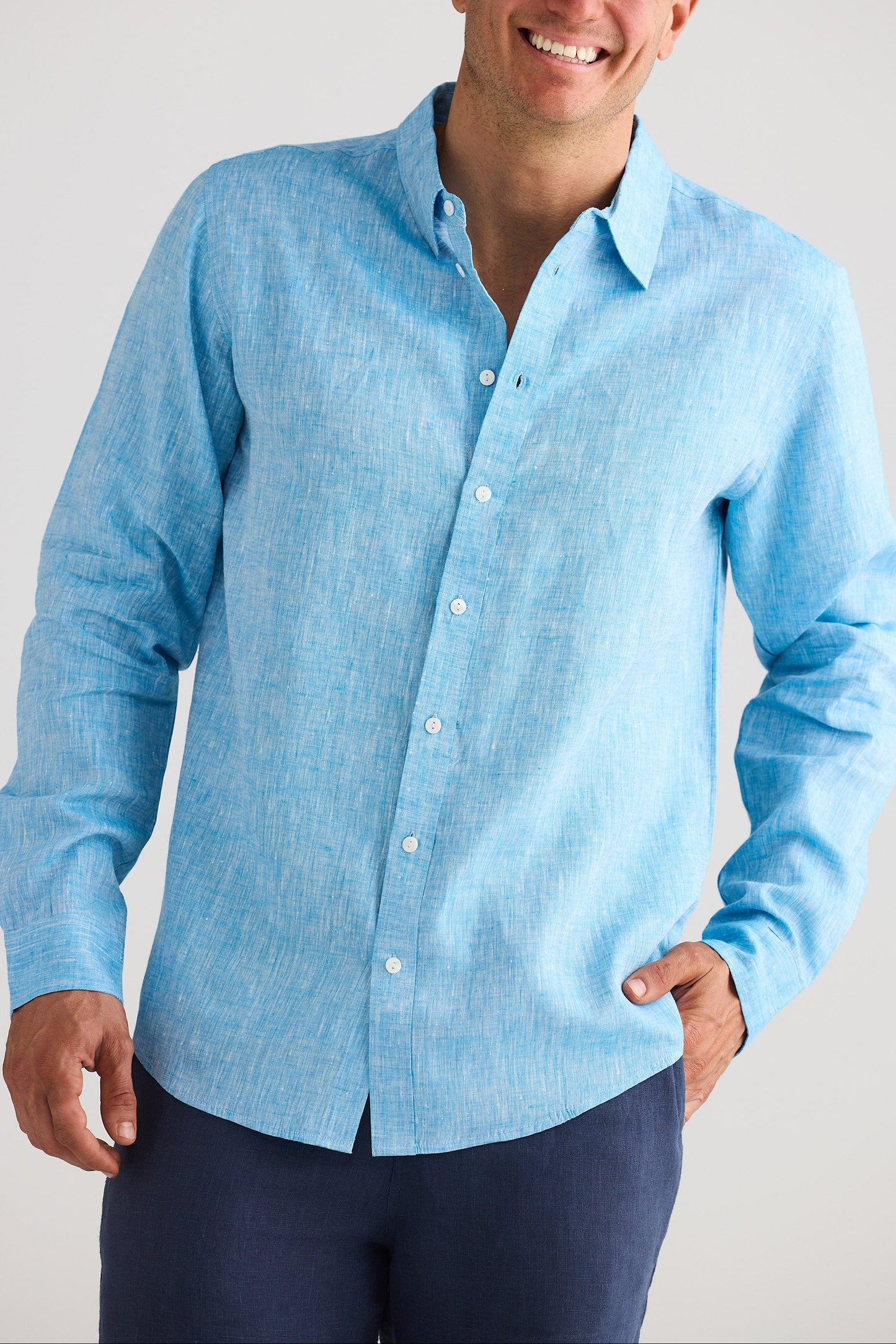 Man wearing a light blue button-up shirt against a plain background