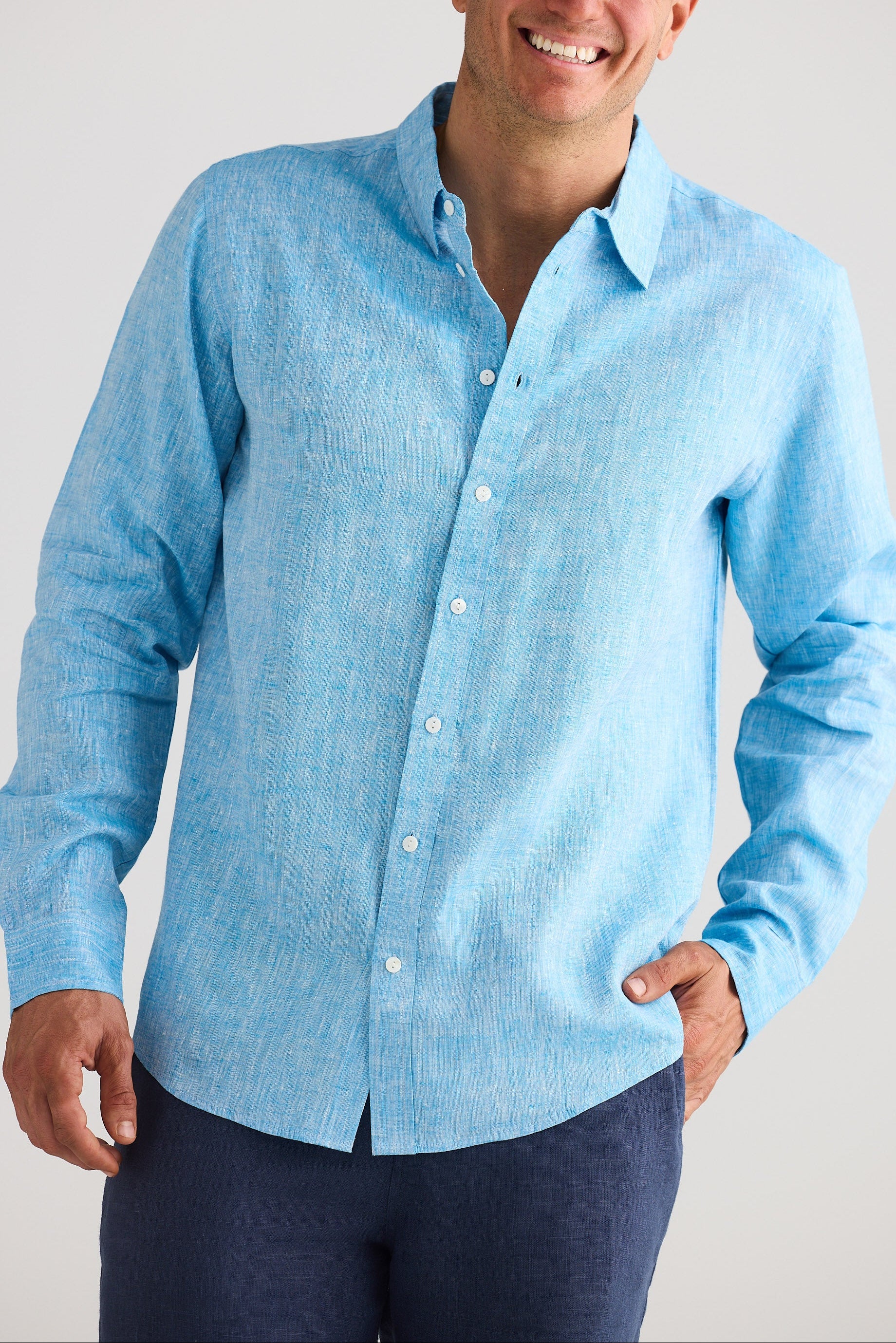 Man wearing a light blue button-up shirt against a plain background