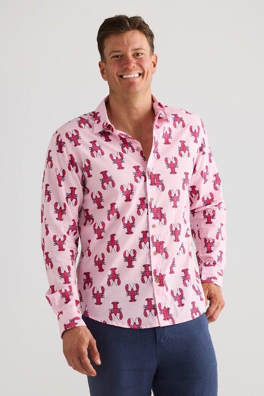 Man wearing a pink shirt with red lobster pattern on a plain background