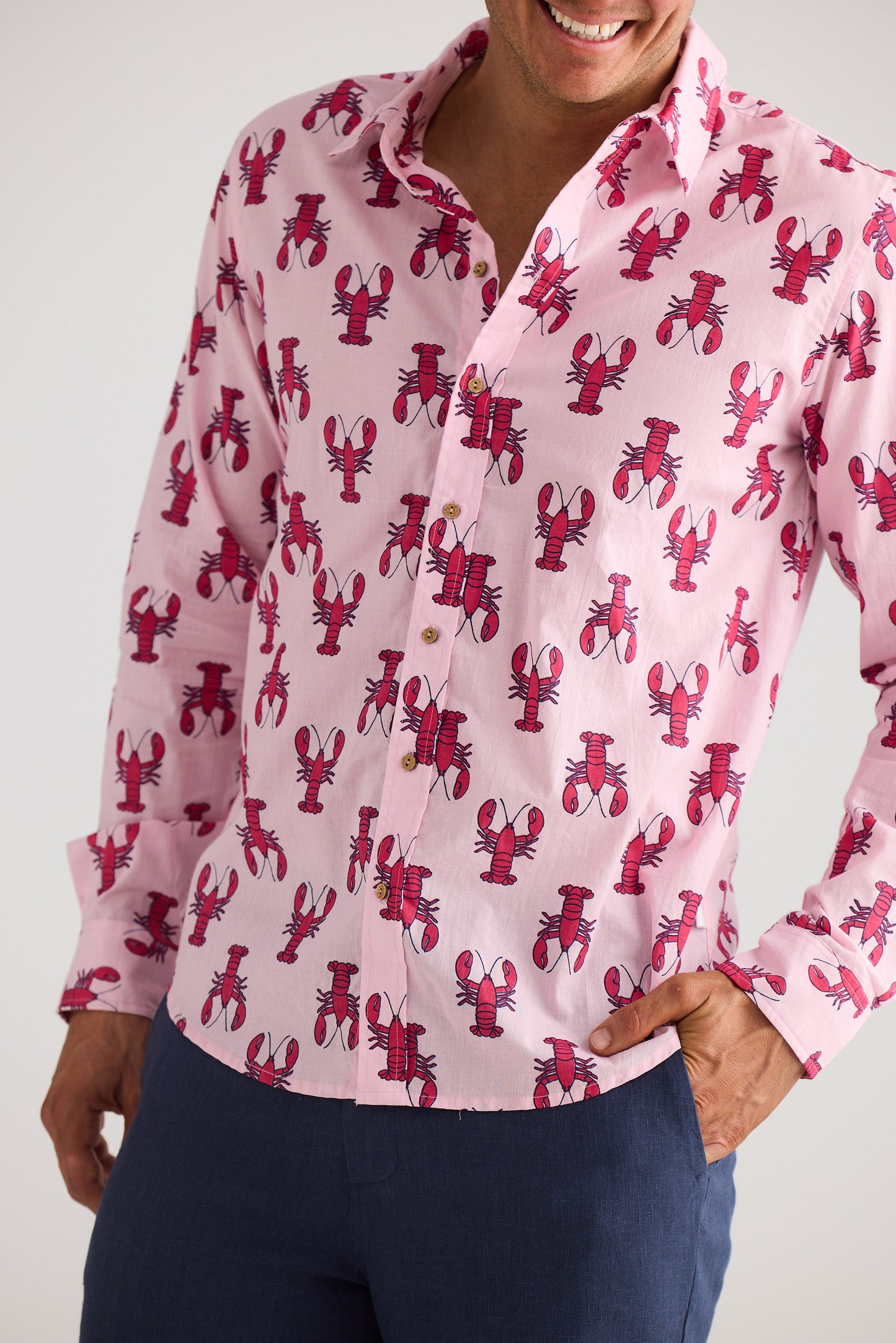 Person wearing a pink shirt with red lobster pattern against a white background