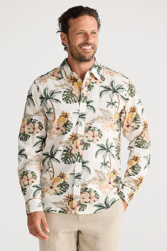 Man wearing a tropical patterned shirt and beige shorts on a white background