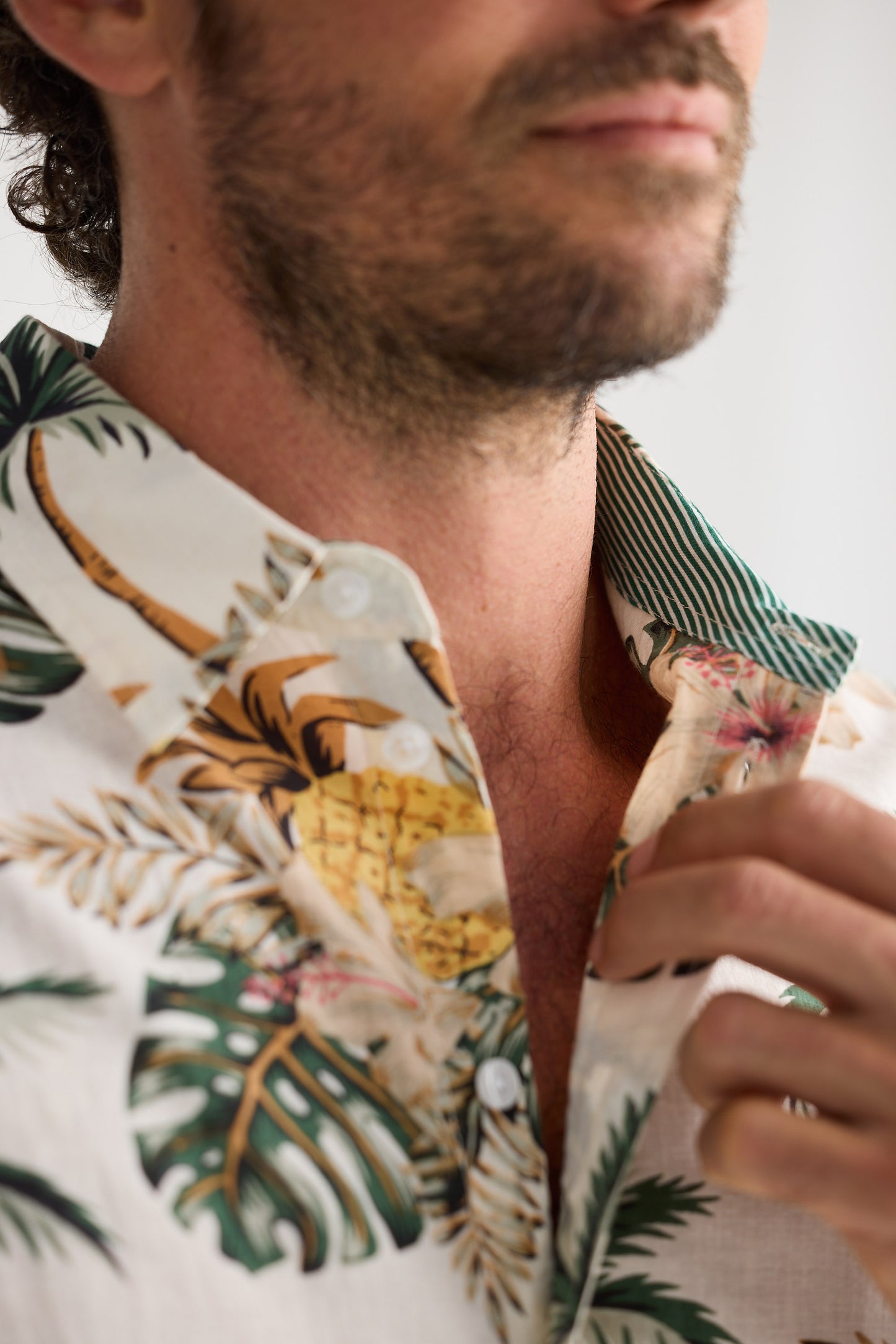 Close-up of a person wearing a tropical shirt with pineapple and leaf patterns.