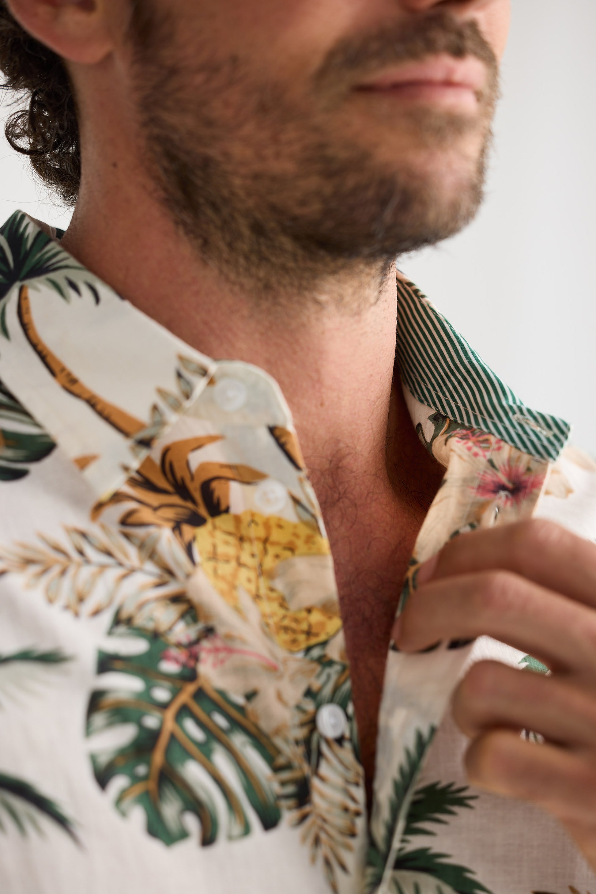 Close-up of a person wearing a tropical shirt with pineapple and leaf patterns.