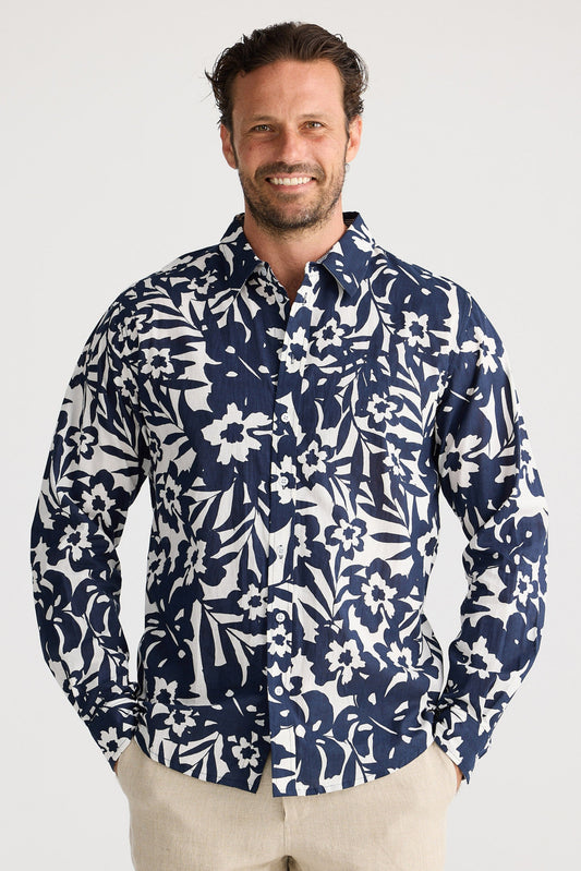 Man wearing a navy floral shirt and beige shorts on a white background