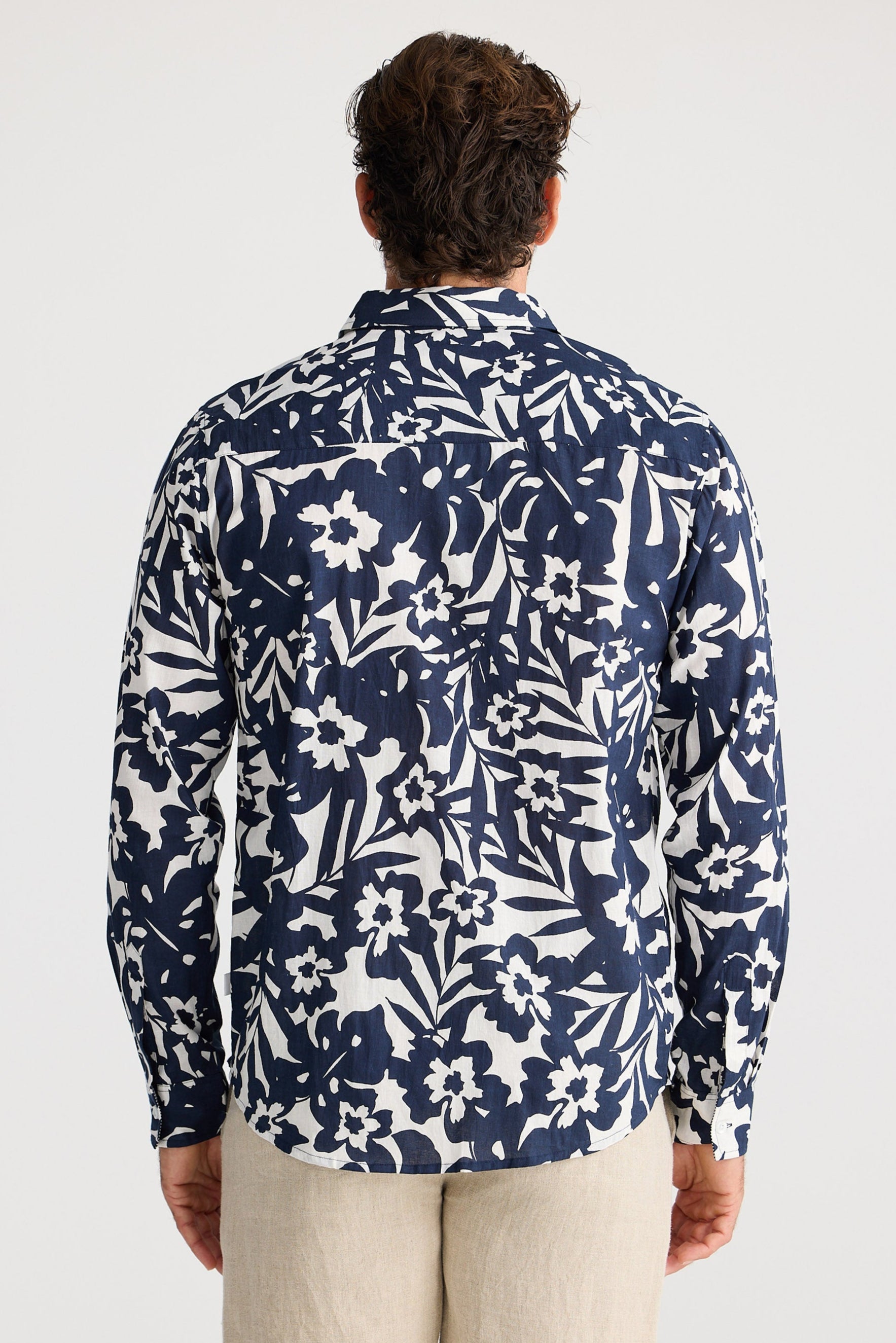 Person wearing a navy floral patterned shirt on a white background