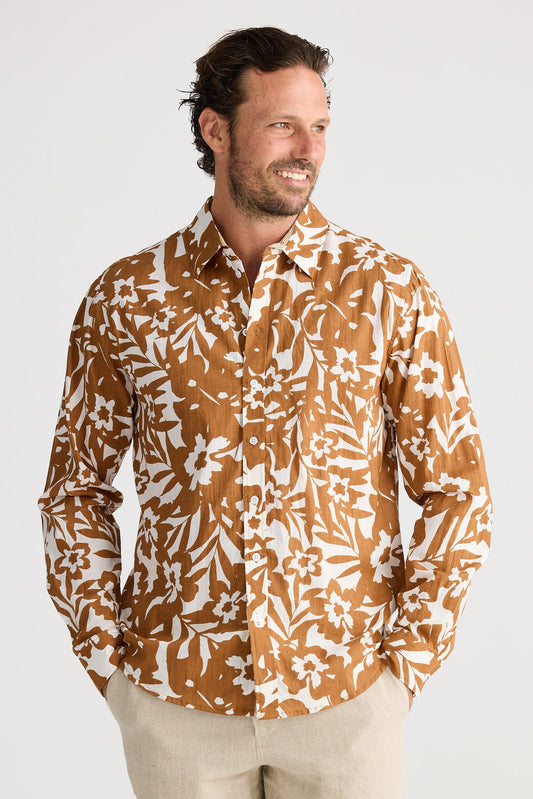 Man wearing a patterned shirt and shorts on a white background