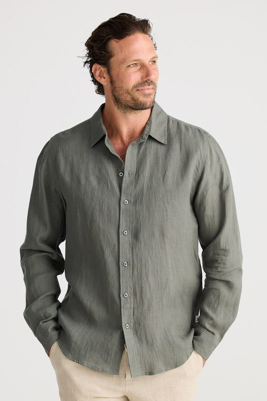 Man wearing a green button-up shirt and beige shorts on a white background