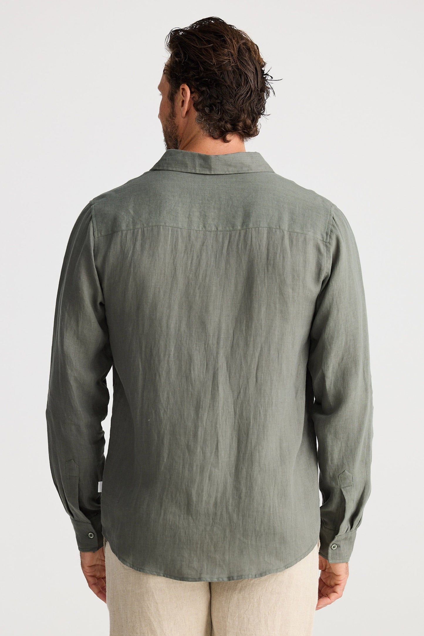 Man wearing a green shirt and beige shorts on a white background