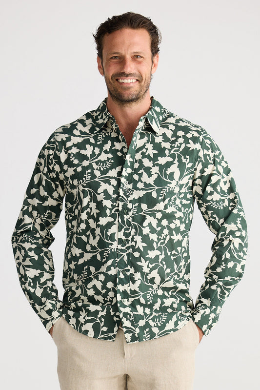 Man wearing a green floral patterned shirt and beige shorts on a white background