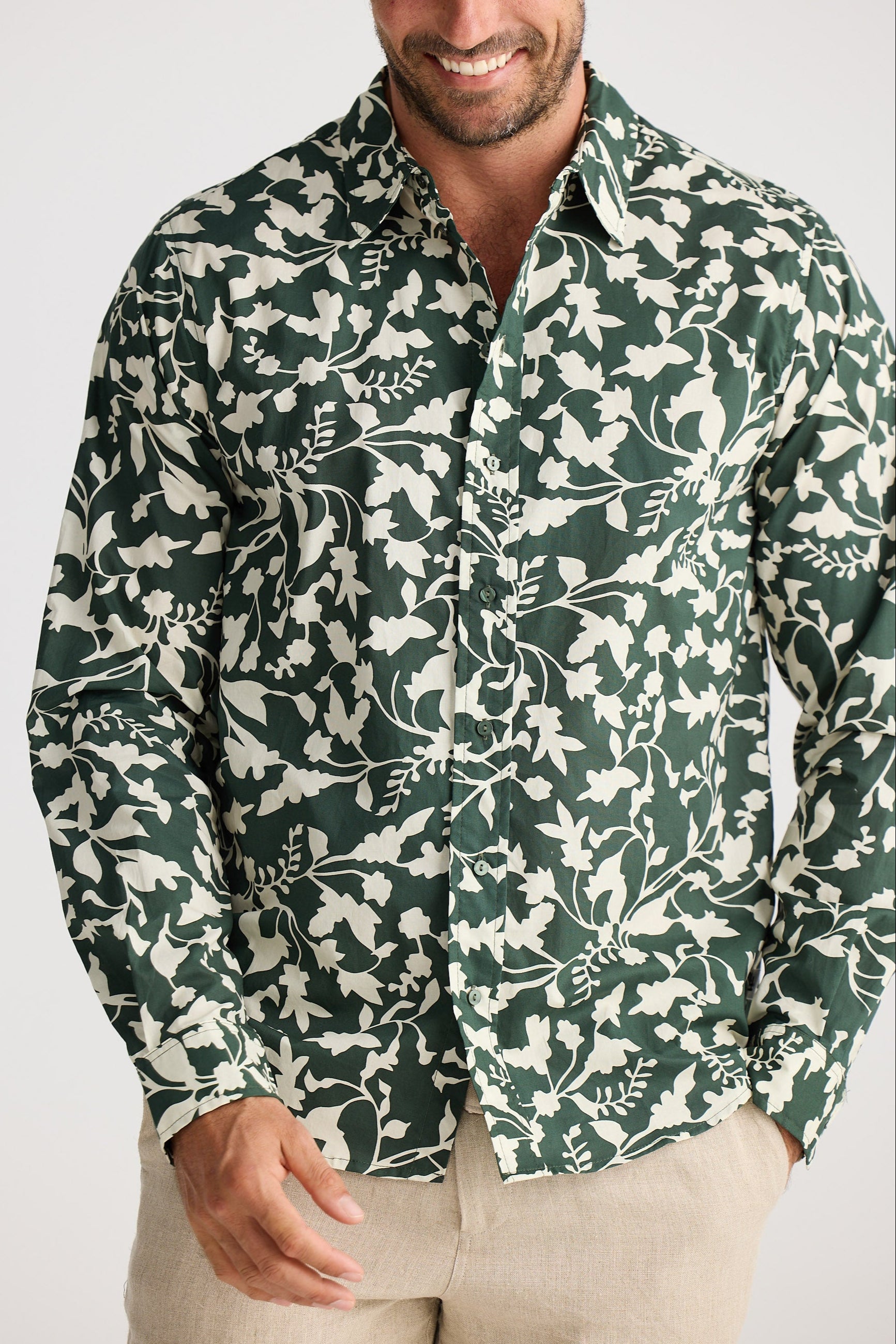 Man wearing a green and white floral patterned shirt on a plain background