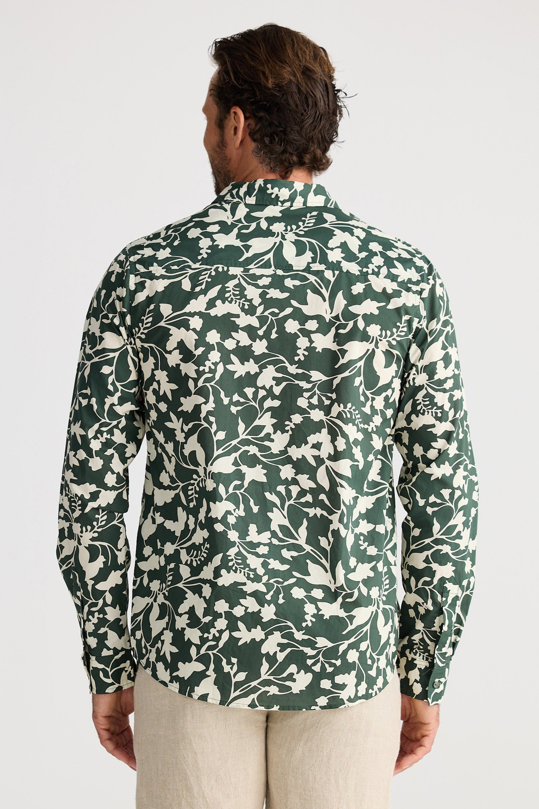 Man wearing a green floral patterned shirt on a white background