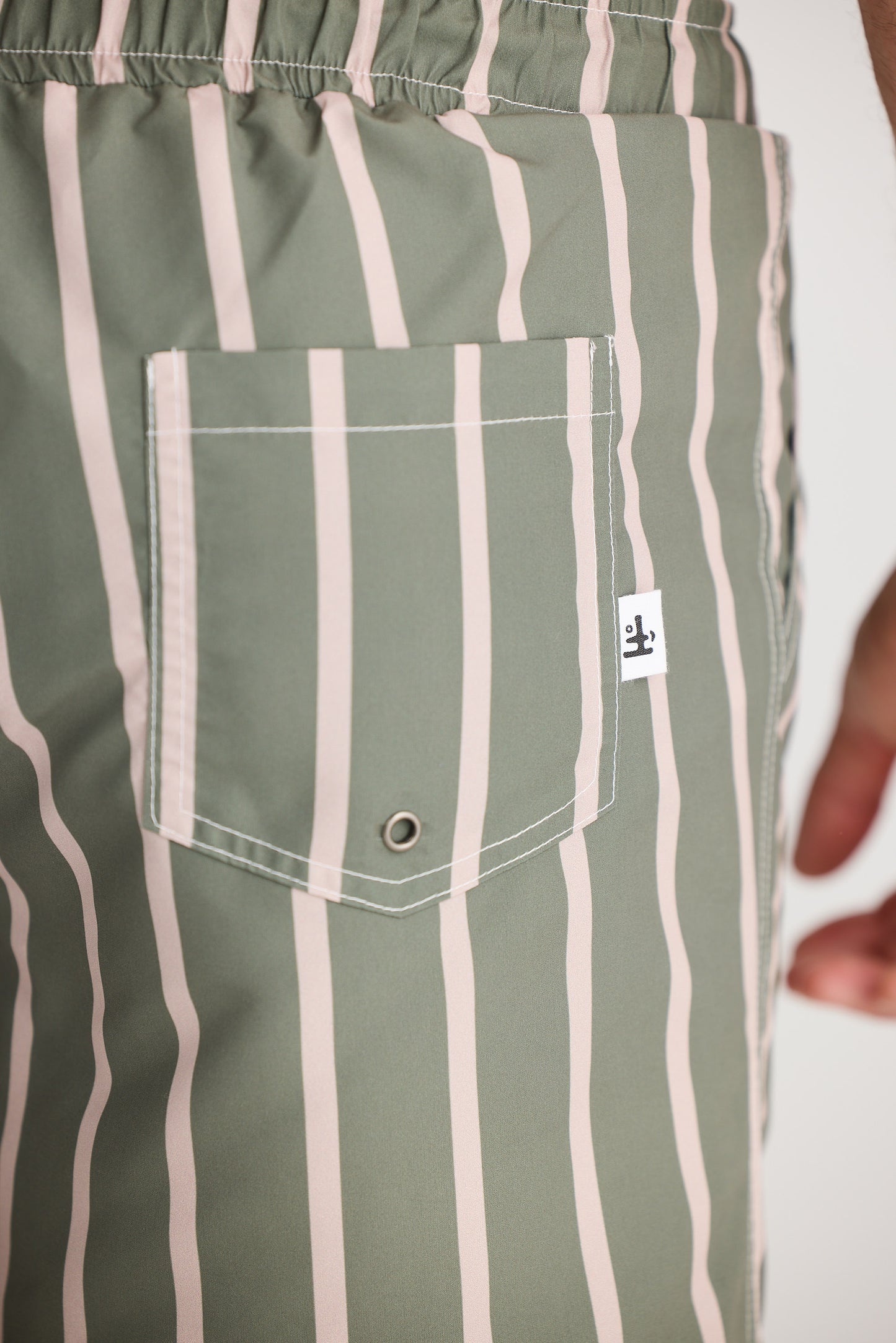 Green and white striped pants with a pocket and brand label.