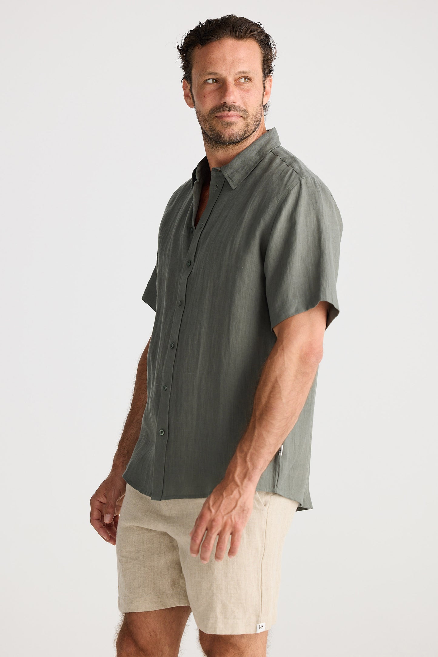 Man wearing a gray short-sleeve shirt and beige shorts on a white background