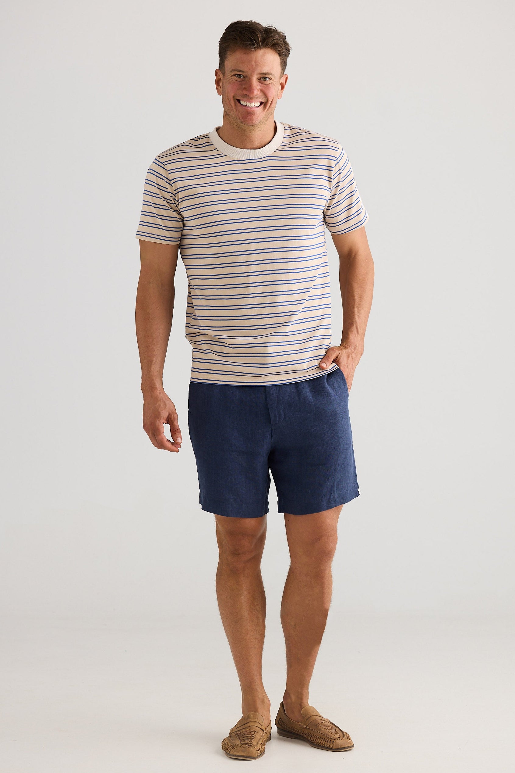 Man wearing a striped t-shirt and navy shorts on a white background