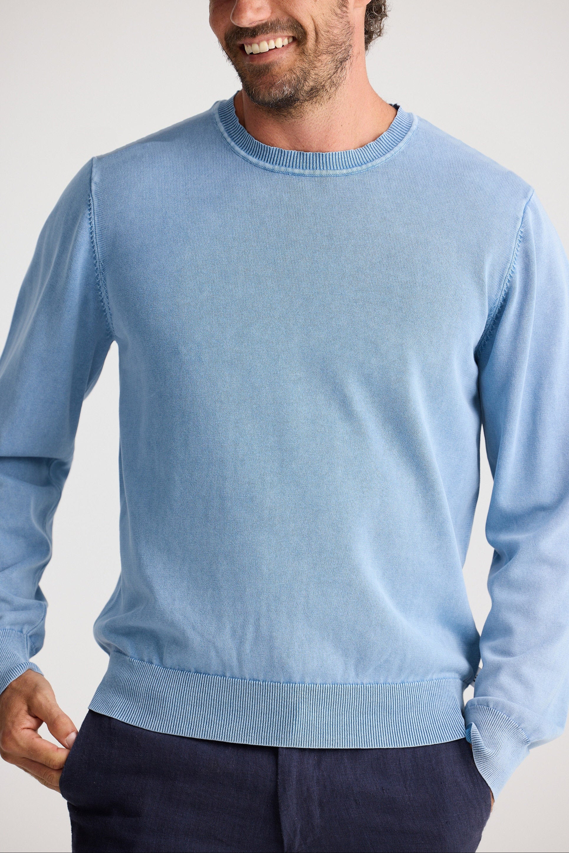 Man wearing a light blue sweater against a plain background