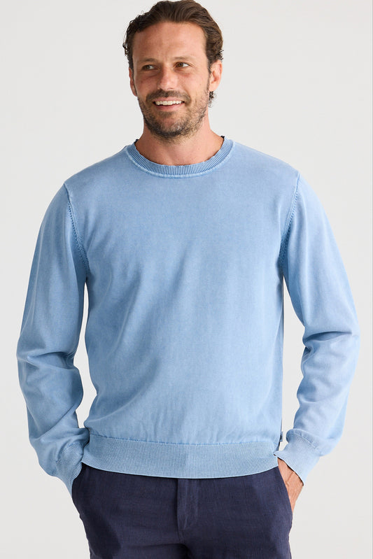Man wearing a light blue sweater against a plain background