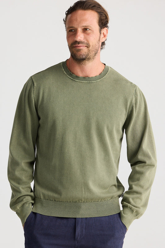 Man wearing a green sweater and navy shorts on a white background