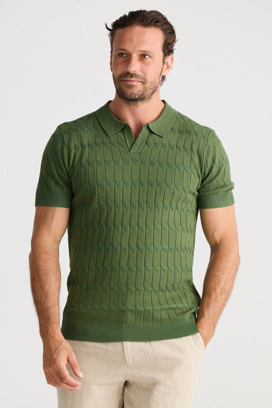 Man wearing a green textured polo shirt and beige shorts on a light gray background