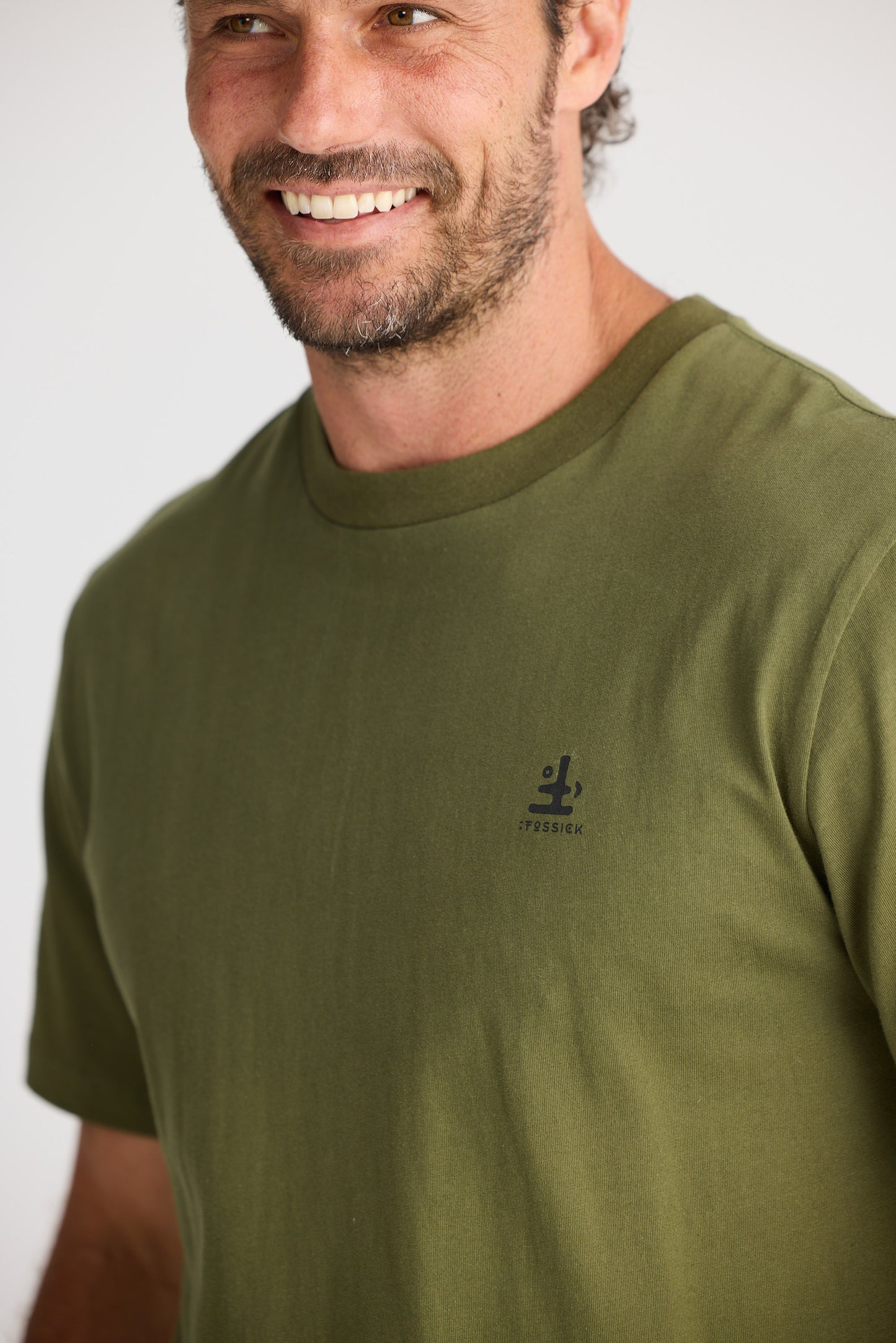 Man wearing a green t-shirt with a logo on a white background