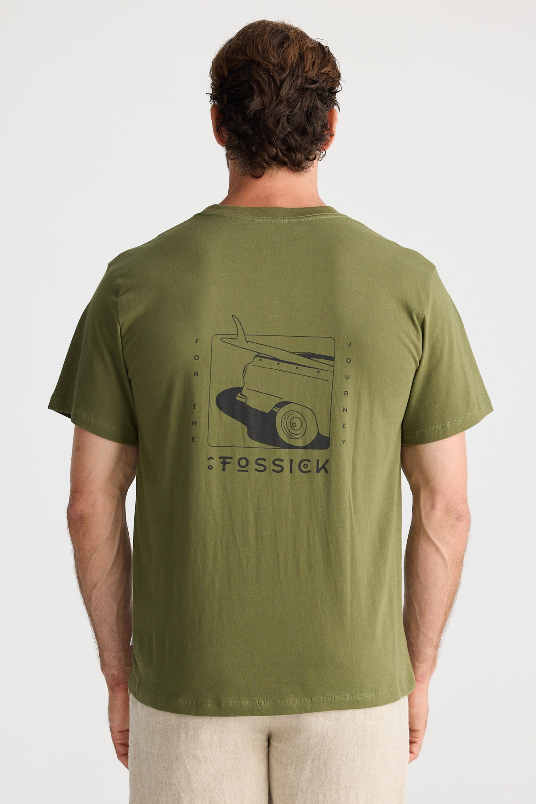 Man wearing a green t-shirt with a logo and text on the back, standing against a white background