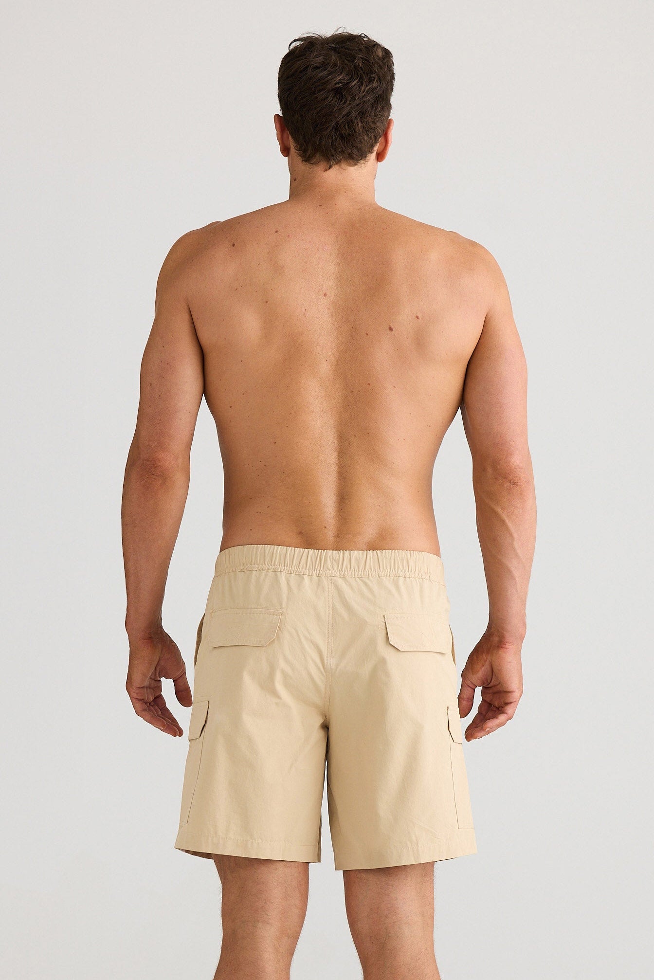 Man wearing beige shorts on a plain background