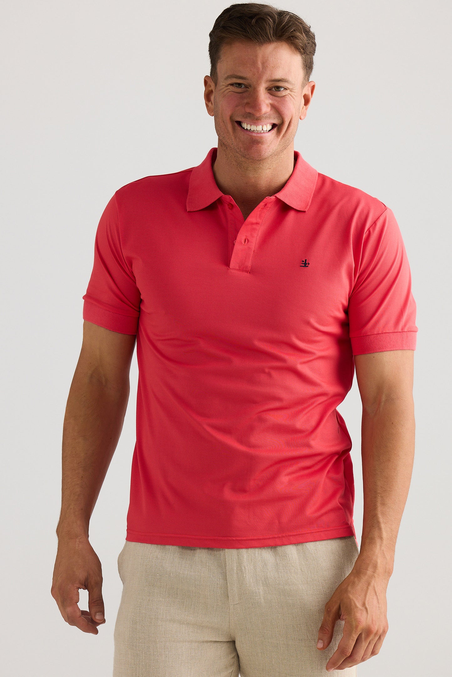 Man wearing a red polo shirt with a visible brand logo on a plain background