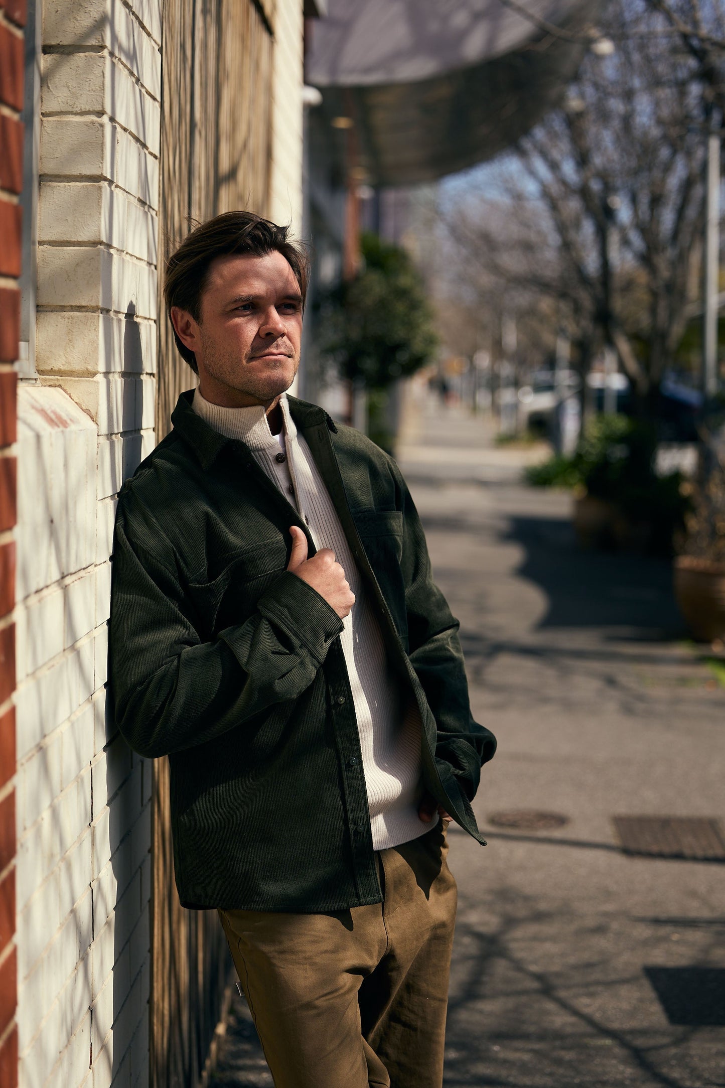 Man leaning against a wall on a sidewalk