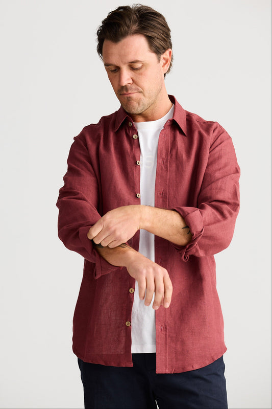 Man wearing a red shirt over a white t-shirt on a plain background
