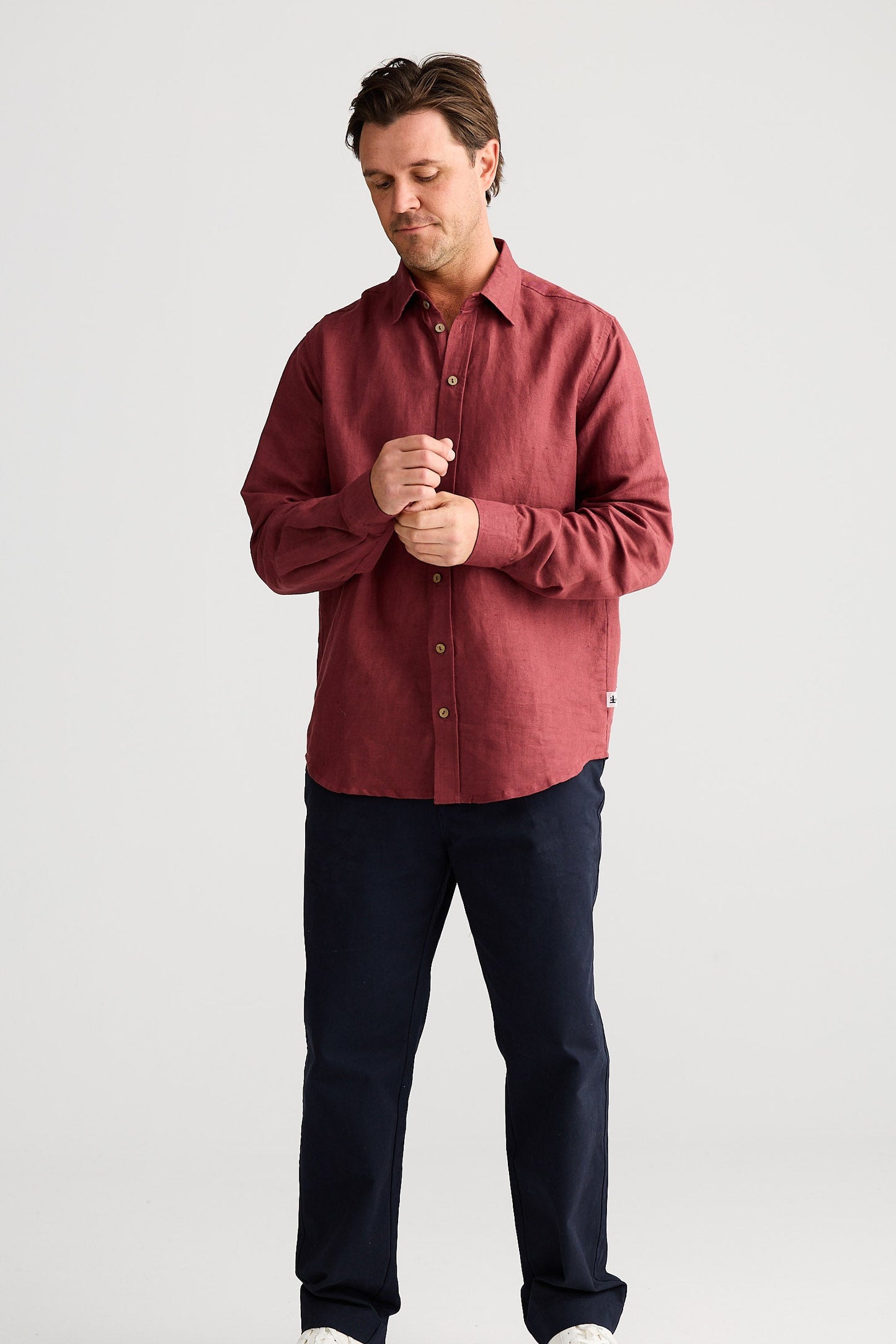 Man wearing a red shirt and dark pants on a white background