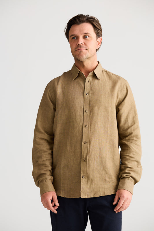 Man wearing a beige button-up shirt against a plain background