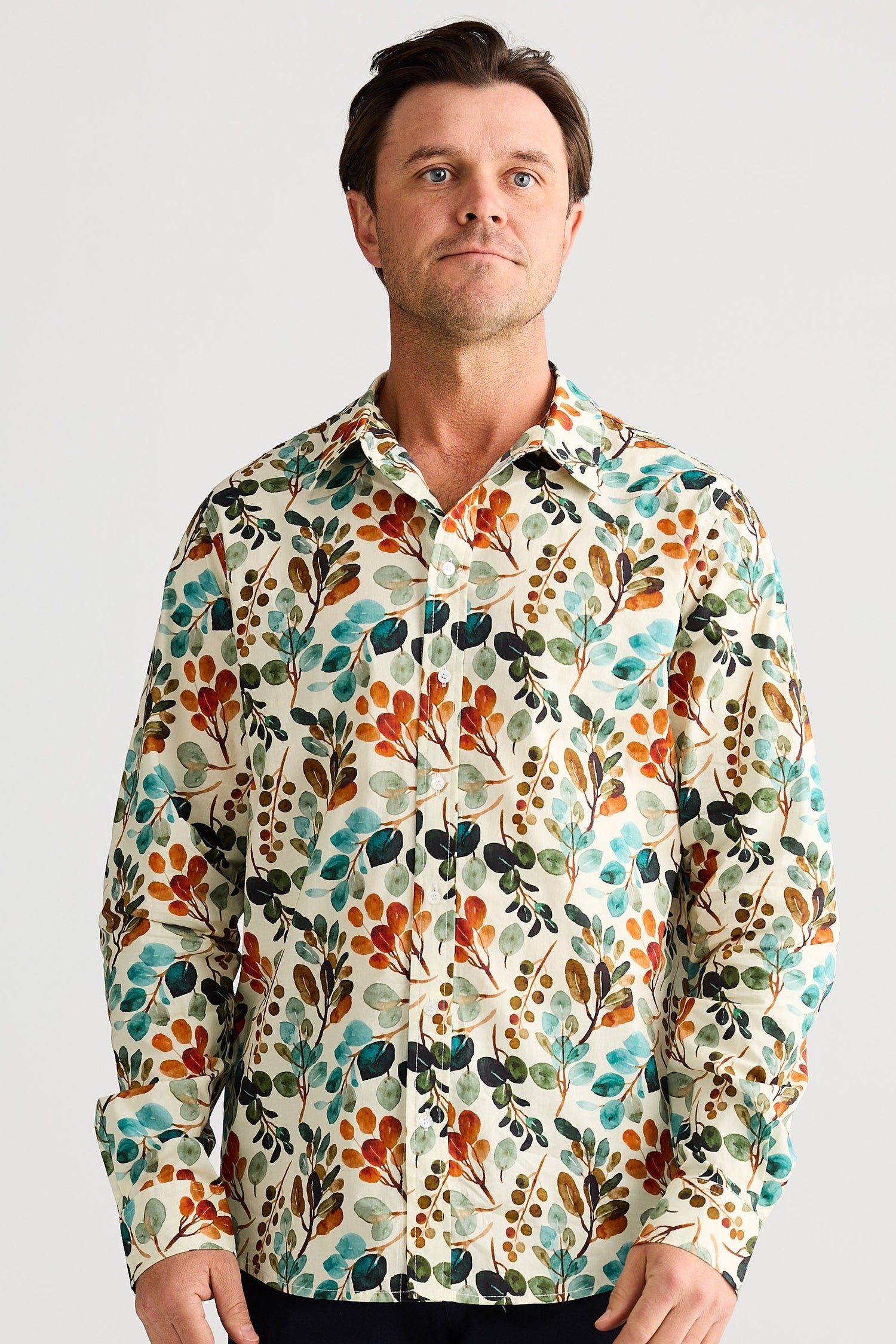 Man wearing a colorful floral patterned shirt against a plain background
