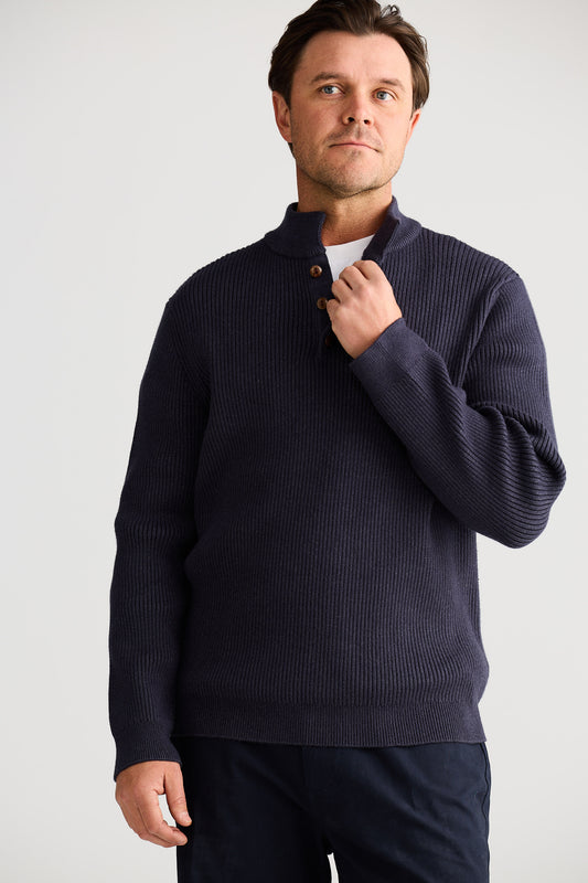 Man wearing a navy blue sweater against a plain background