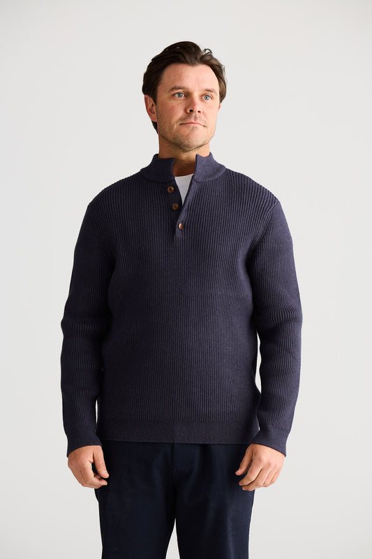 Man wearing a navy blue sweater with a white background