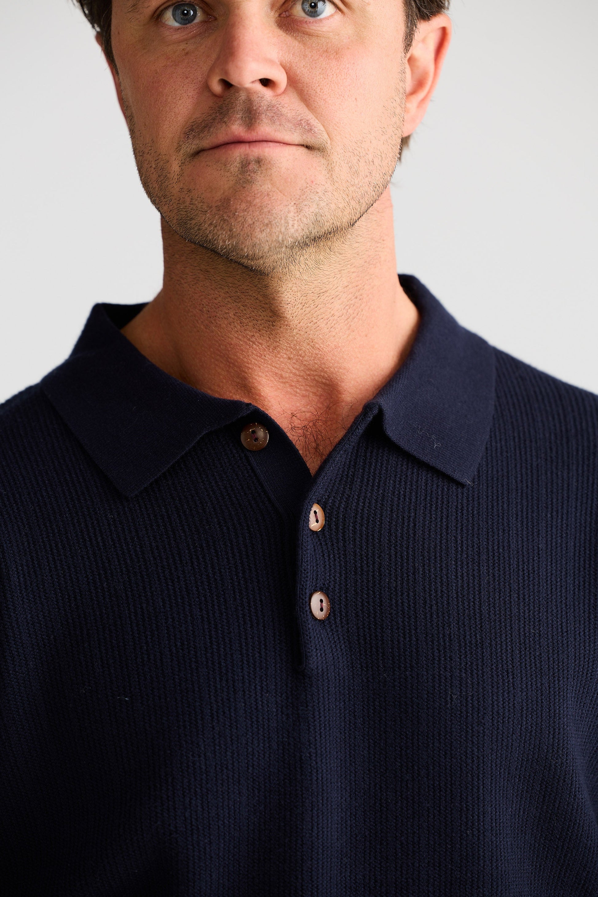 Man wearing a navy blue polo shirt against a plain background